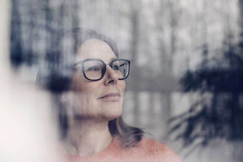 close-up-of-thoughtful-businesswoman-wearing-eyeglasses-seen-through-window
