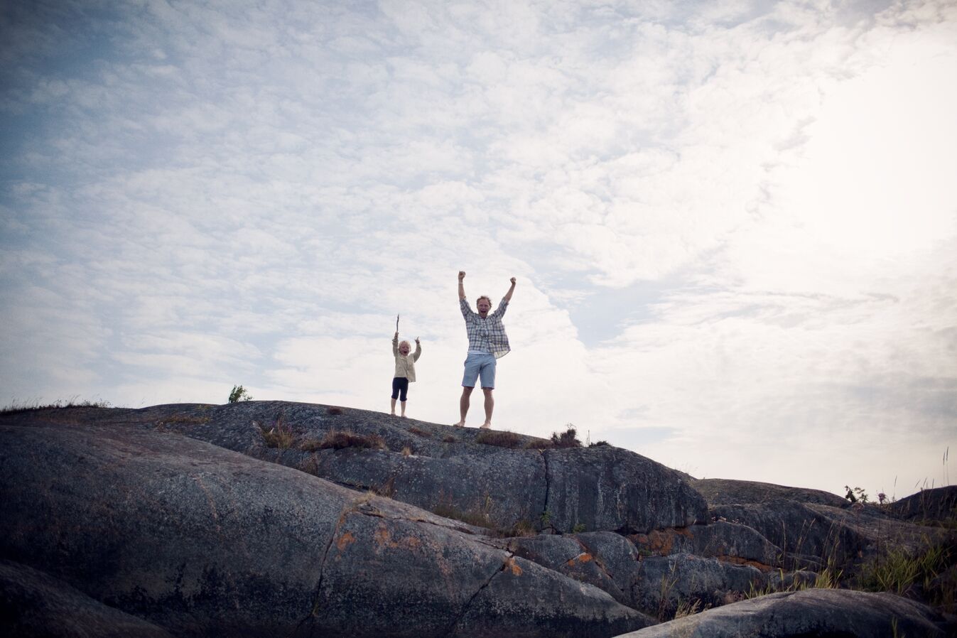 father-and-son-standing-on-rocks-with-arms-stretched