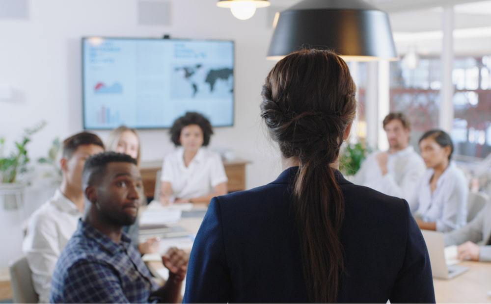 A woman standing in front of a group of people and presenting.