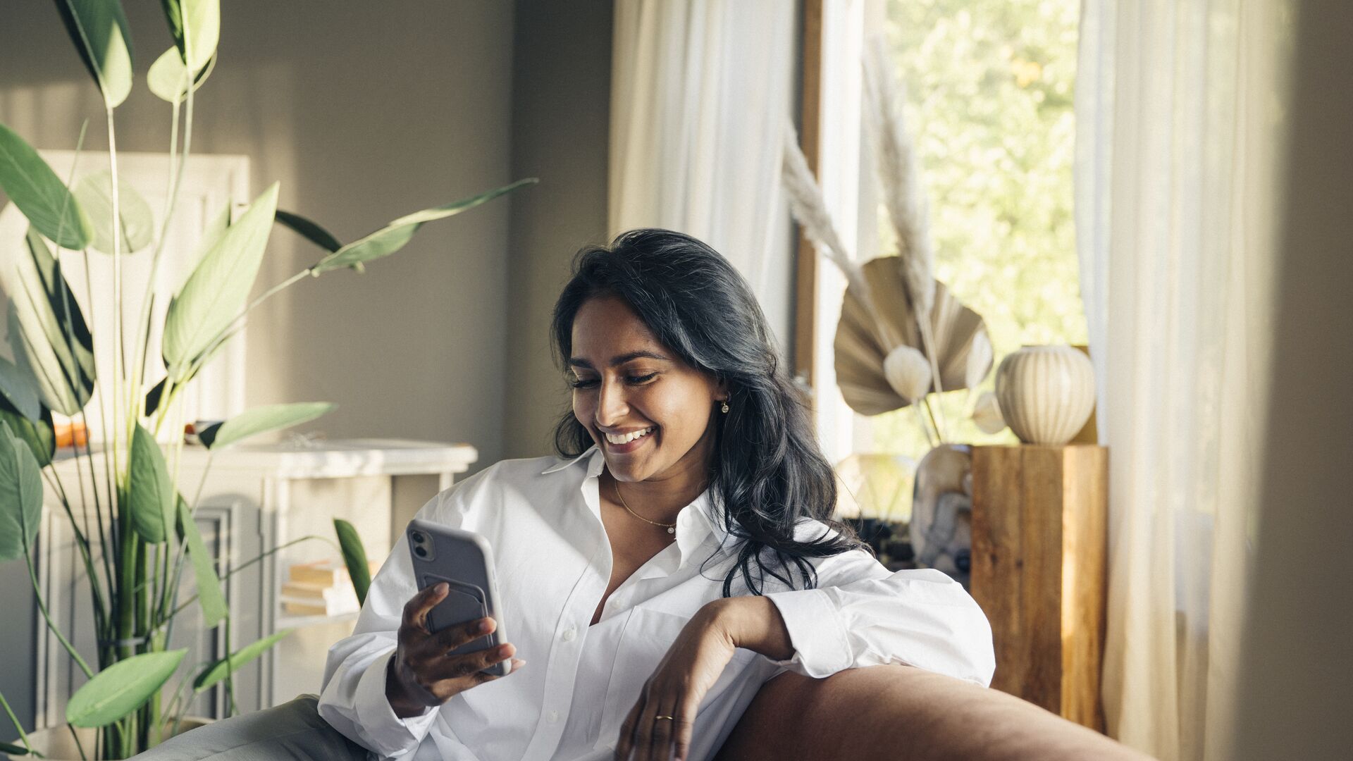 Woman sitting in sofa looking at phone