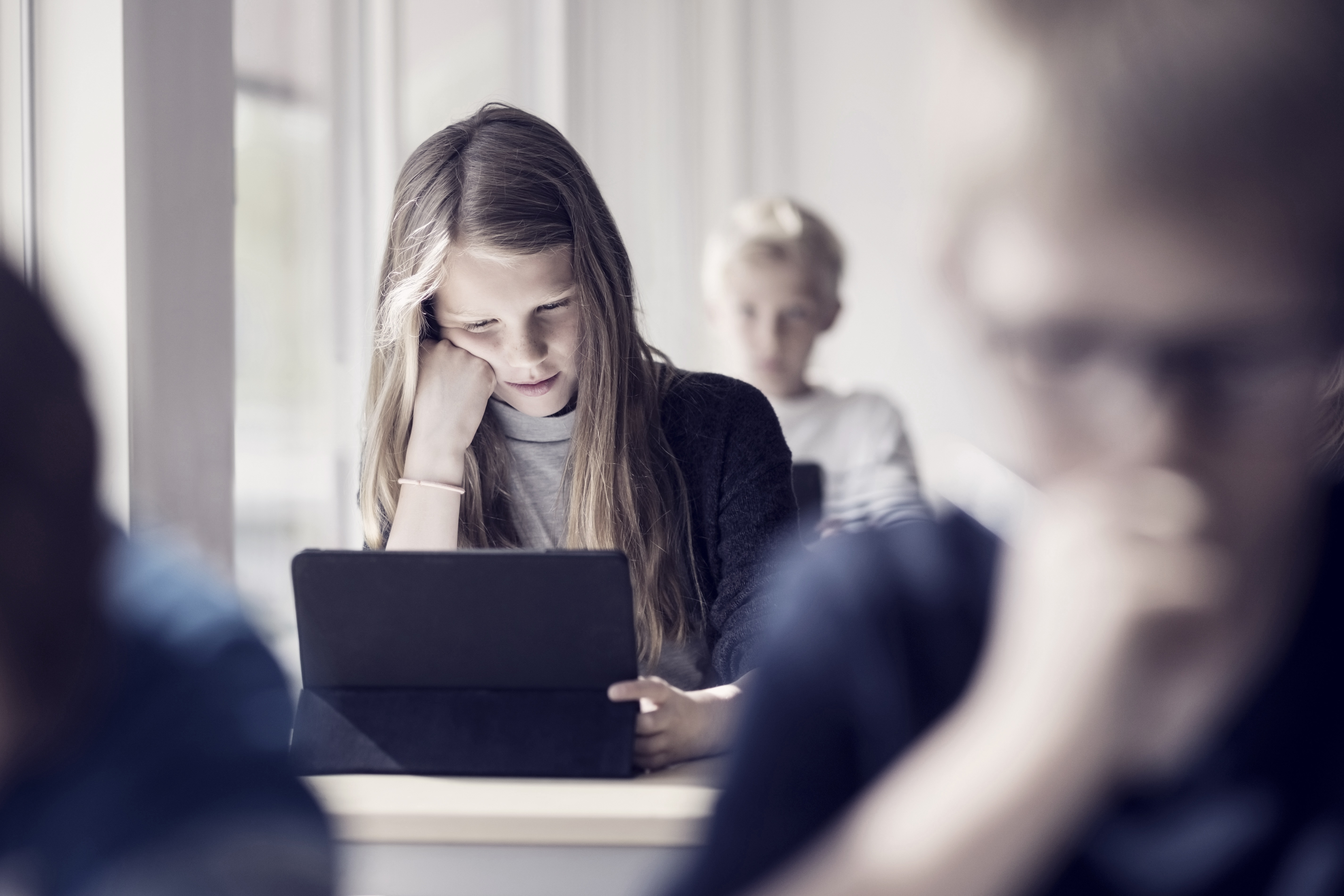 Girl reading from digital tablet for learning in classroom