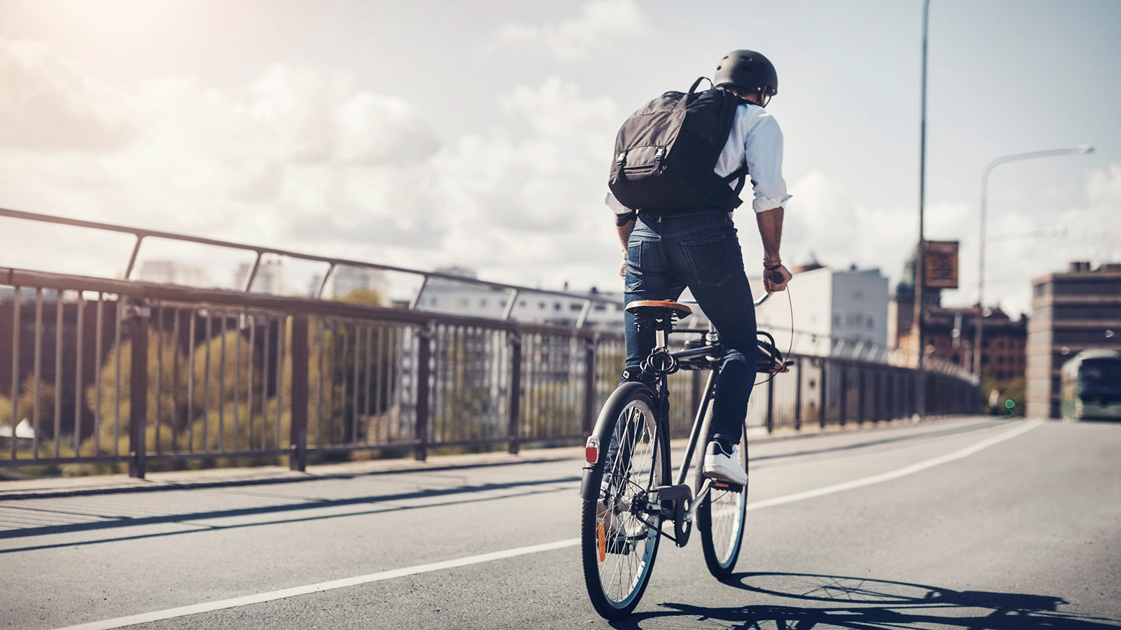 Forretningsmand, der cykler på en bro i byen