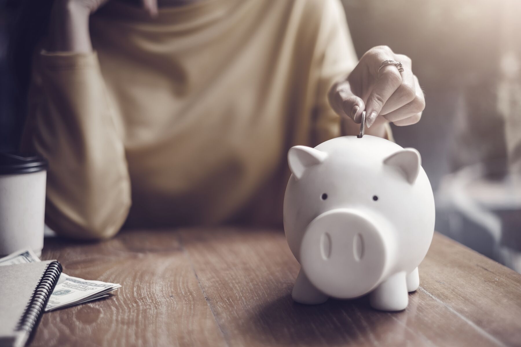 woman-putting-coin-in-piggy-bank.