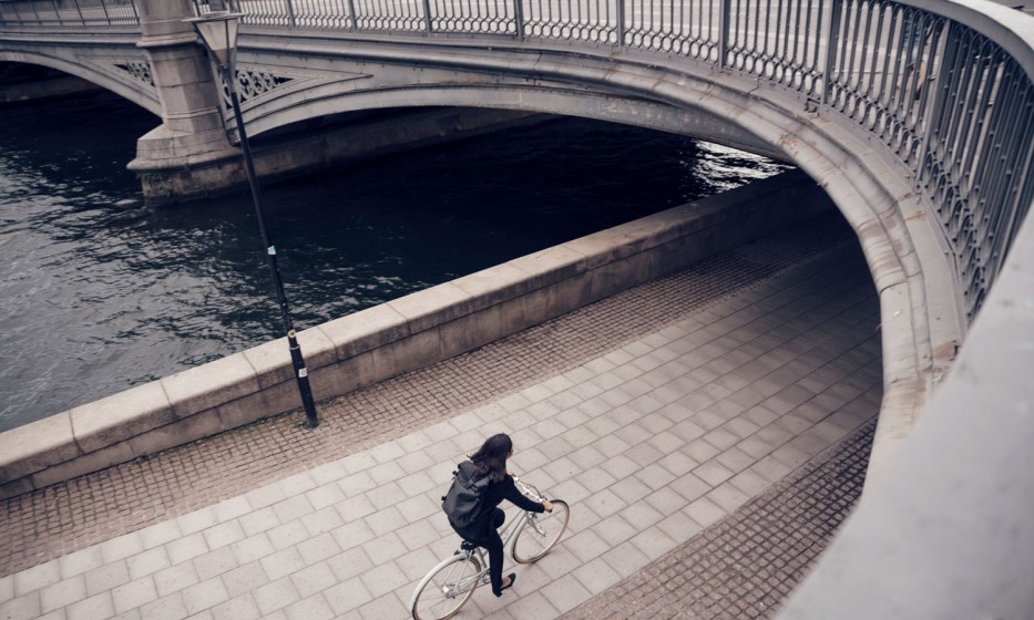 high-angle-view-of-businesswoman-riding-bicycle-on-footpath-by-canal-in-city