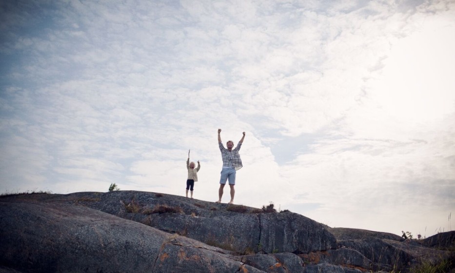 father-and-son-standing-on-rocks-with-arms-stretched