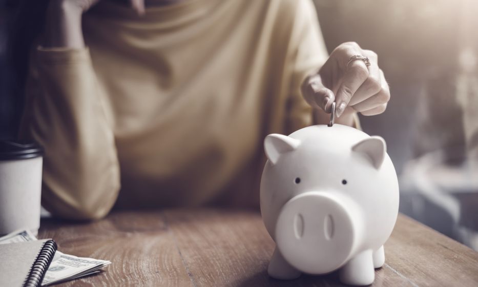 Nainen laittaa kolikon säästöpossuun