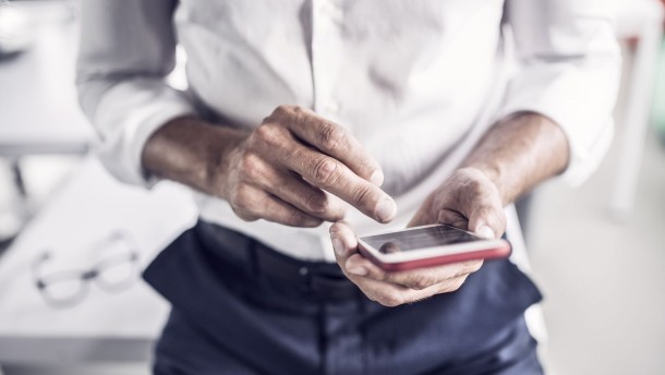 close-up-of-businessman-using-cell-phone-in-office
