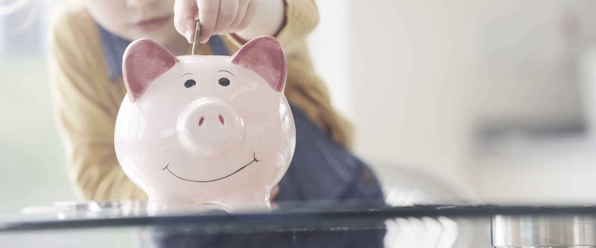 Lapsi laittaa kolikon säästöpossuun