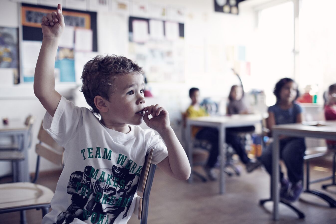 Boy in classroom raising his hand - Nordea Ideell Aktiefond