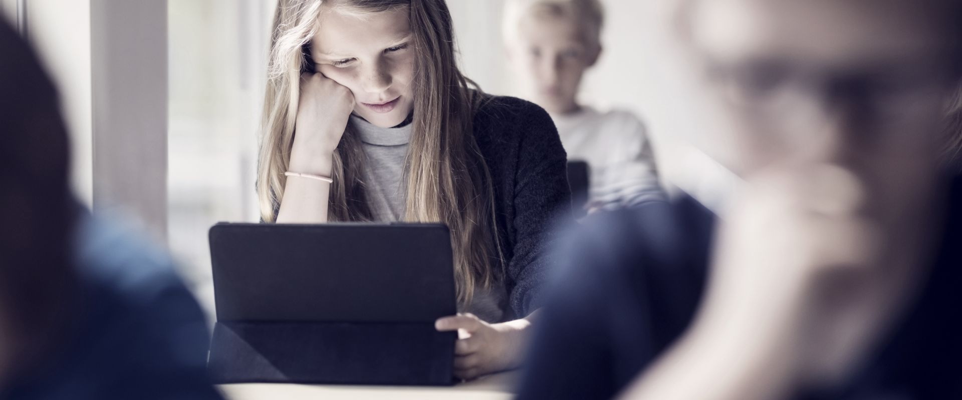 Girl reading from digital tablet for learning in classroom