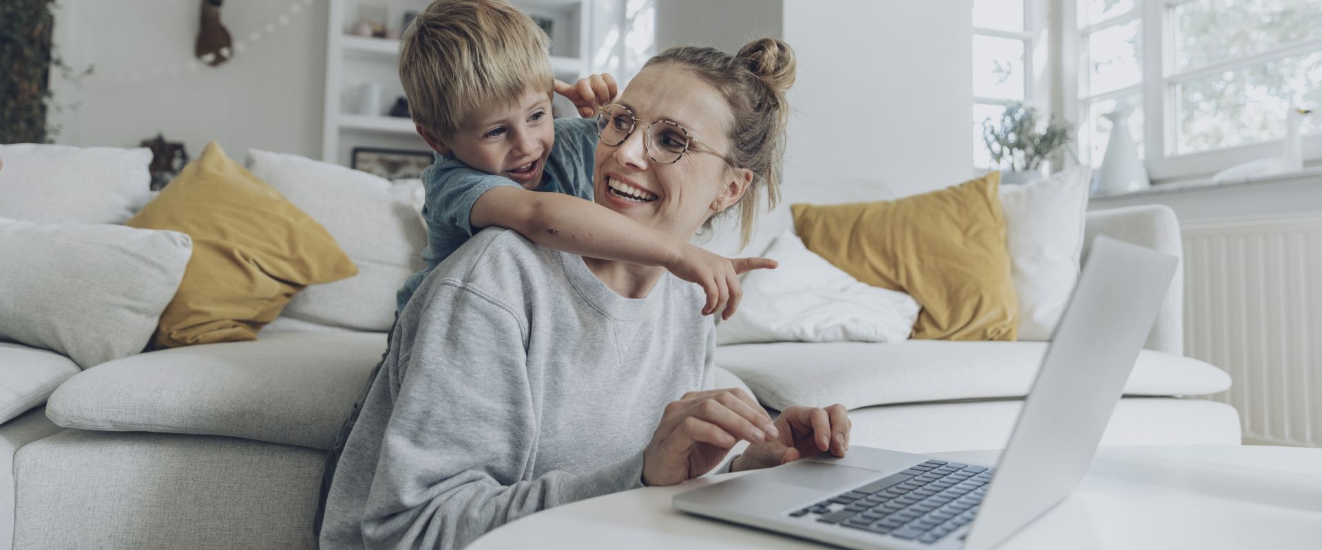 Boy pointing at laptop while standing behind mother at home