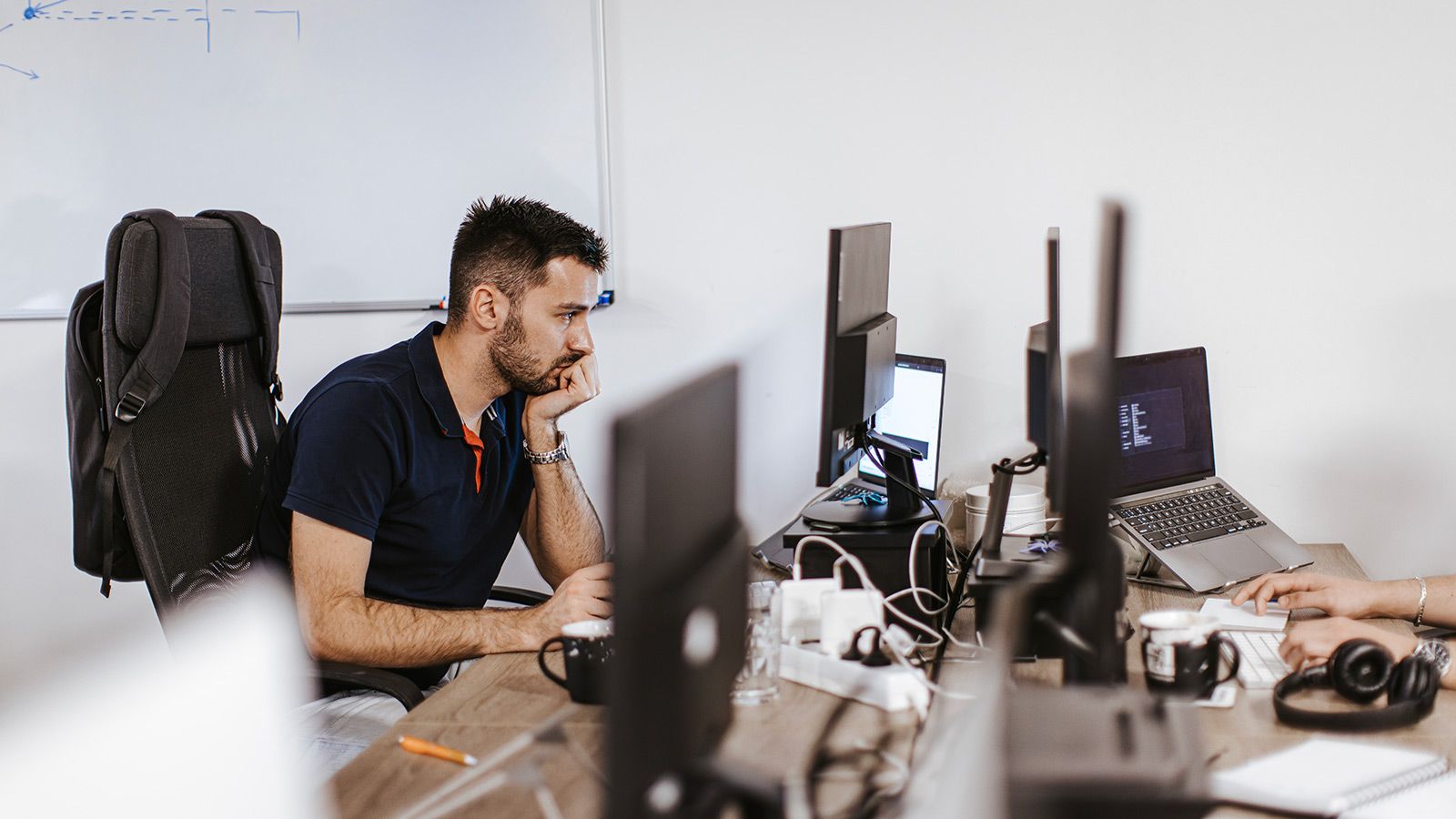 Sidebillede af en ung kaukasisk computerprogrammør, der arbejder på en computer på det moderne kontor