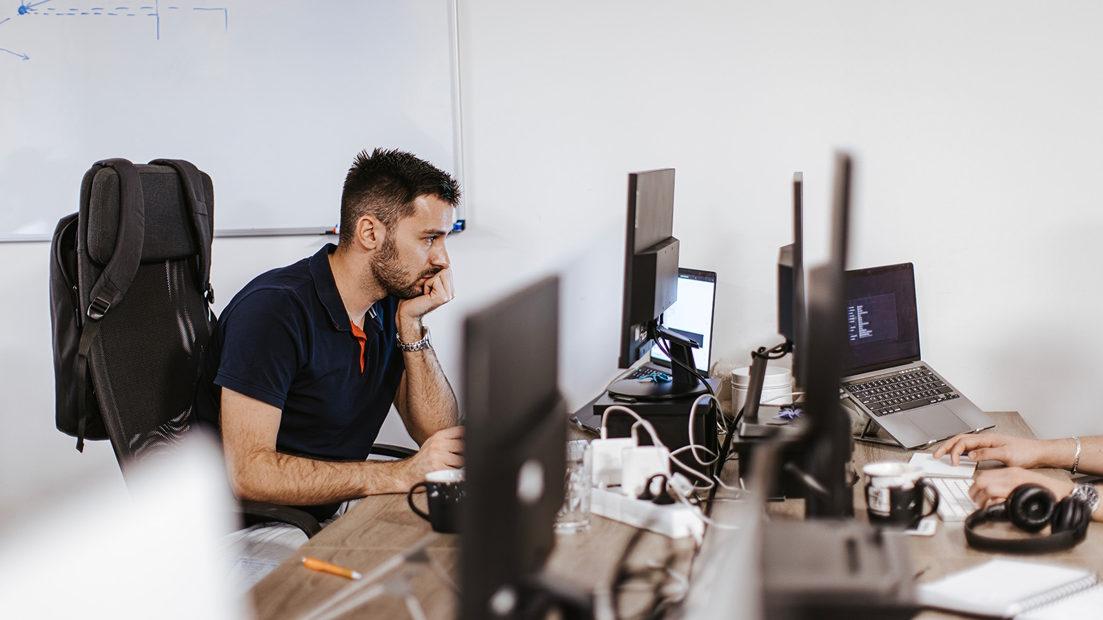 Sidebillede af en ung kaukasisk computerprogrammør, der arbejder på en computer på det moderne kontor