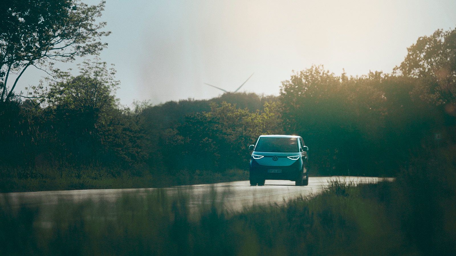 En bil kører på vejen med lav sol i baggrunden