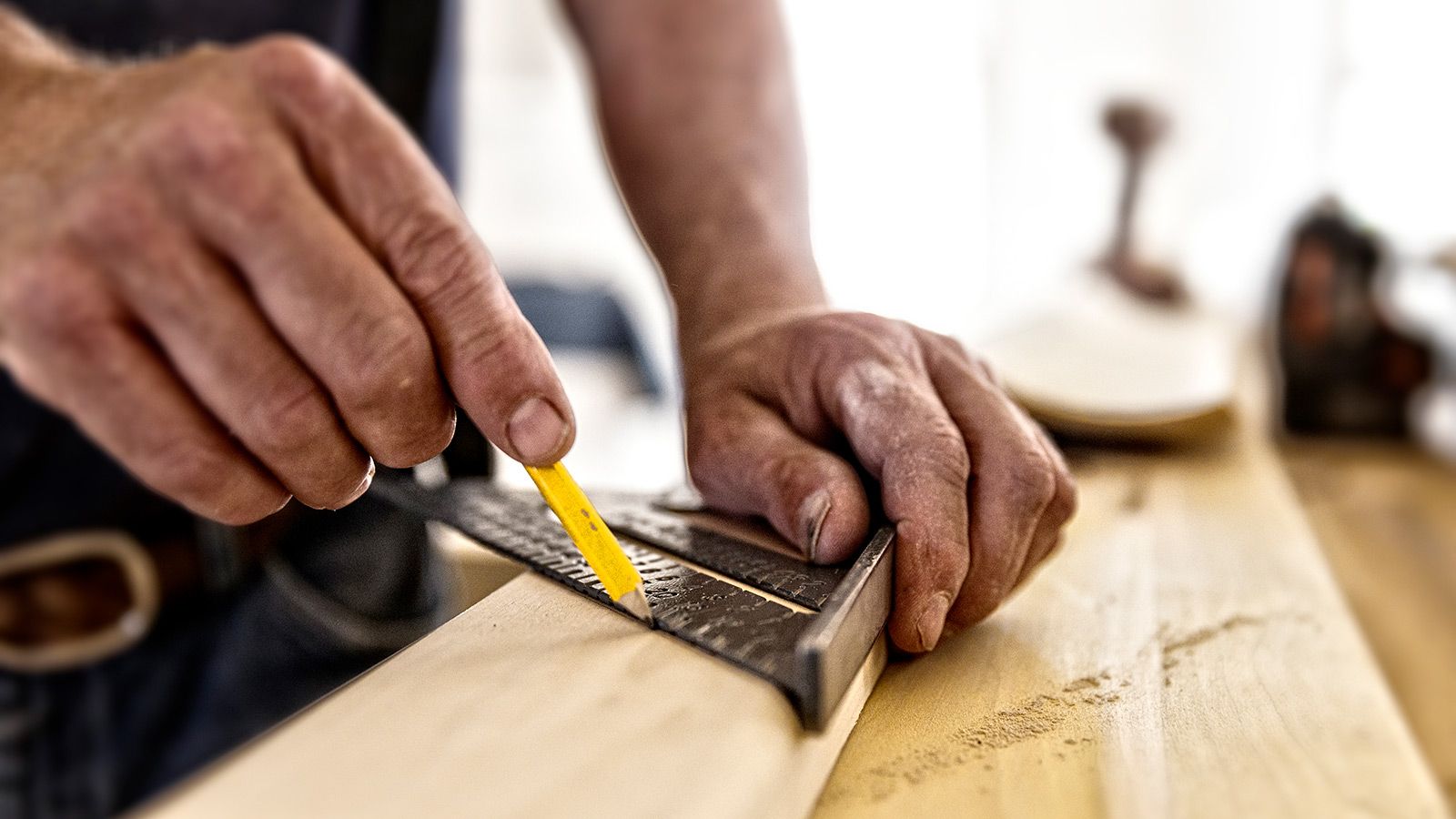 Tømrer bruger en tømrervinkel og en blyant til at afmærke en liste, der skal skæres.