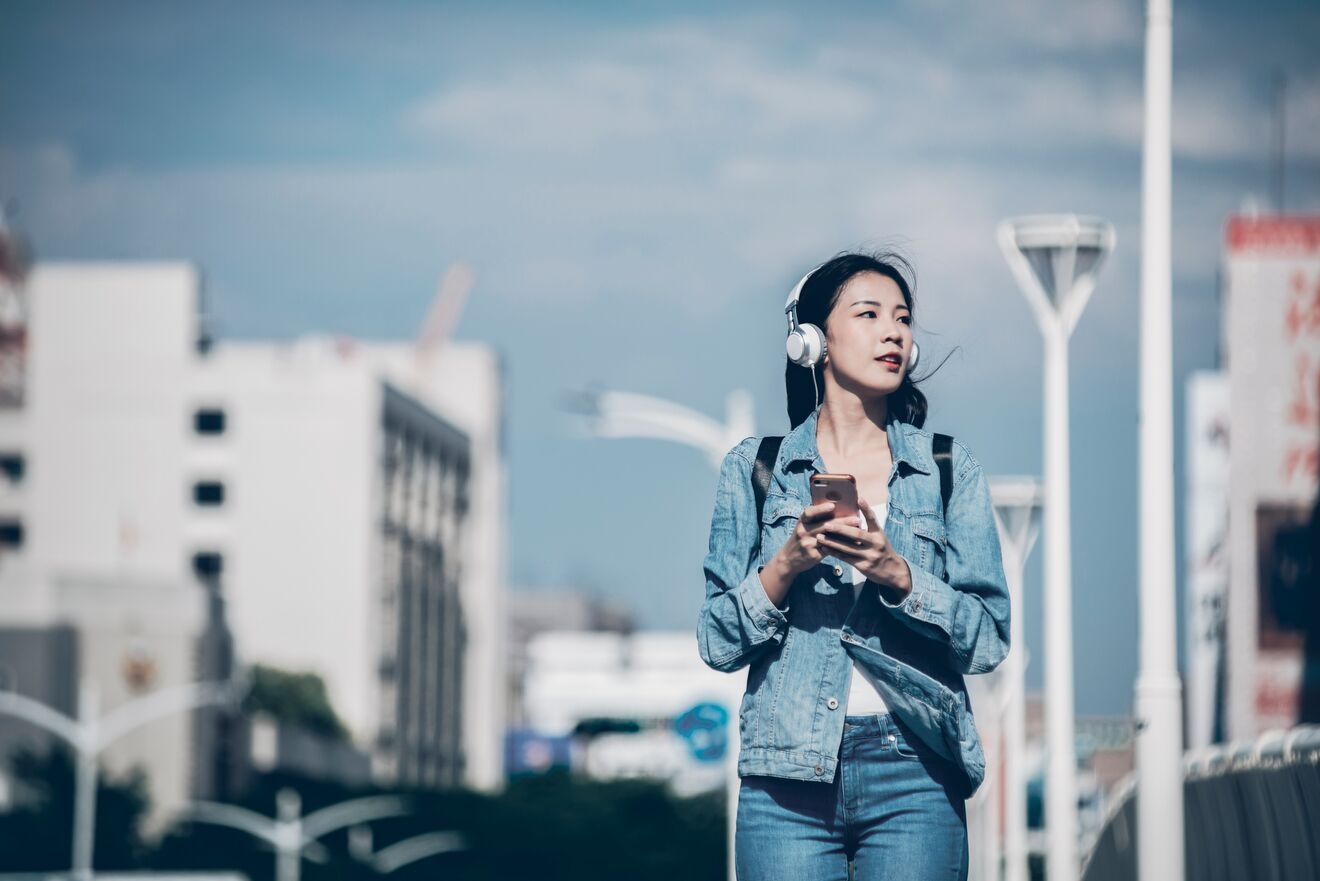 Woman walking on the street and listening to podcast
